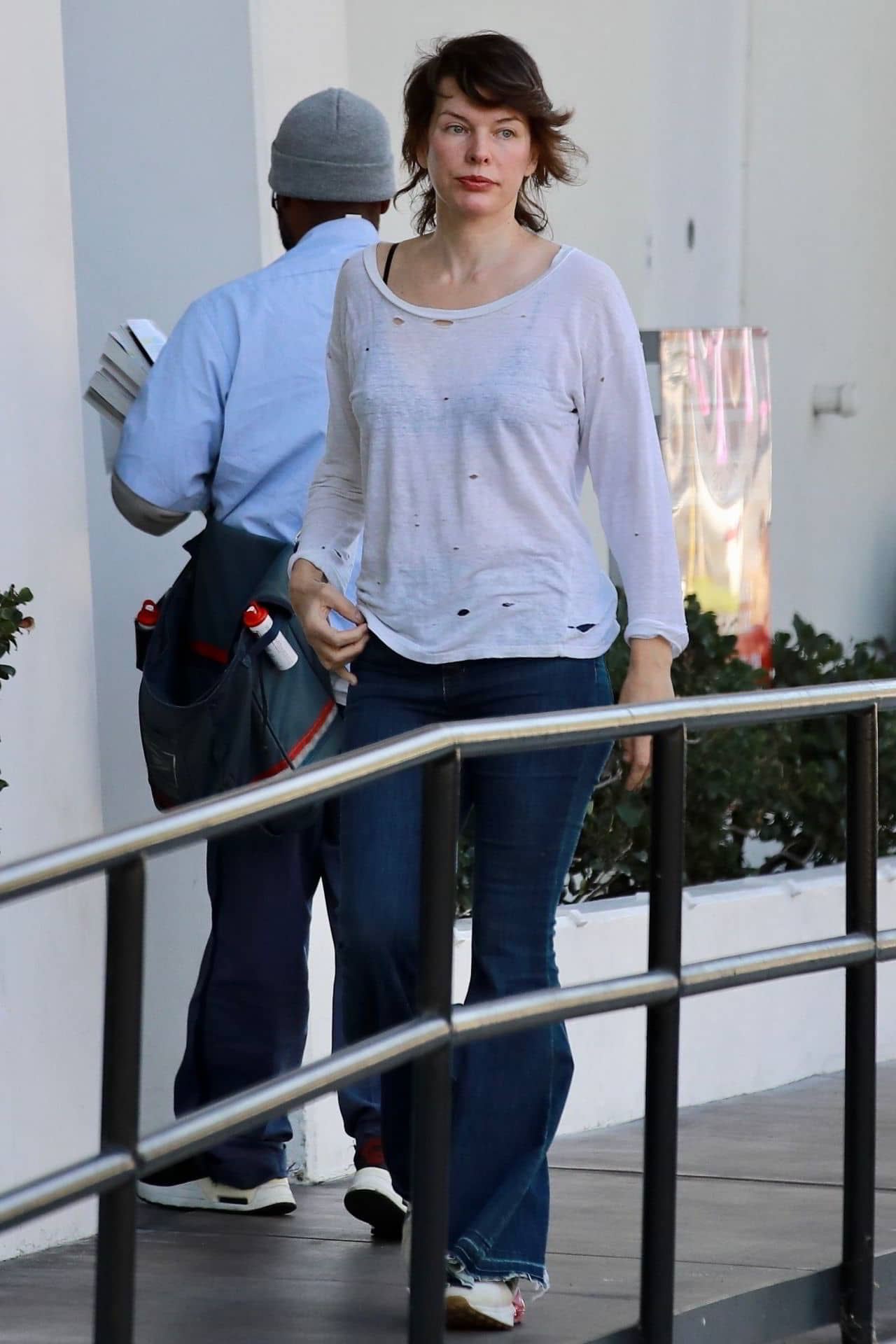 Milla Jovovich in Distressed White Top and Flared Blue Jeans Los Angeles January 2024 - 1